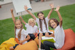 © zinkevych - Group of pupils sitting on chair bags and raising hands