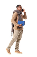 Wall Mural - African-American man with books talking by phone on white background