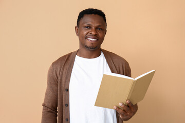 Wall Mural - African-American man reading book on color background