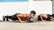 © Atstock Productions - Group of fit male bodybuilders doing bodyweight push up exercise outdoors on building rooftop