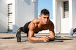 © Atstock Productions - Shirtless muscular sports man doing plank workout exercise in the open air on building rooftop floor