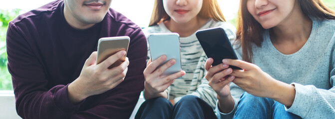 Wall Mural - Group of young people using and looking at mobile phone while sitting together