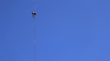 Wall Mural - A man walks along the highline against the blue sky, Highliner goes on a stretched sling, Tightrope walker, A man catches balance.