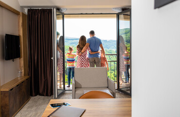 Wall Mural - rear view of smiling family of four in the hotel room standing at terrace.
