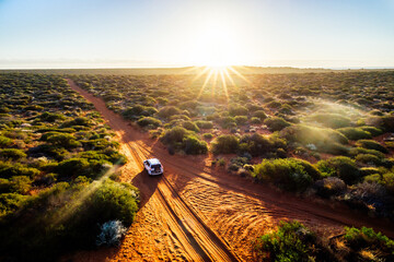 australia, red sand unpaved road and 4x4 at sunset, freedom outback