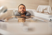 Bearded Young Man Taking Bath In Spa Salon