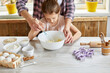© bondarillia - Mother teaching daughter prepare dough together in kitchen