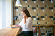 Focused brunette woman using laptop and talking on smartphone. Professional female designer sitting and discussing project with client via mobile phone. Freelance and digital technology concept