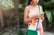 © mary_markevich - young sexy beautiful woman in colorful dress, summer hippie style, tropical vacation, holding smartphone, texting, earrings, hands close up