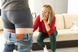 Man stands in shorts next to woman with magnifying glass, looking at her crotch in surprise. Male health examination and psychological problems in intimate life concept