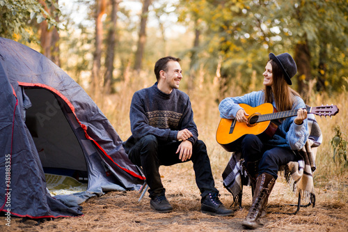 Cuadros en Lienzo Portrait of young couple sitting on camp chair with guitar near camp tent