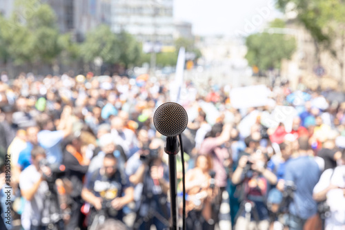 Cuadros en Lienzo Focus on microphone, blurred group of people at mass protest in the background