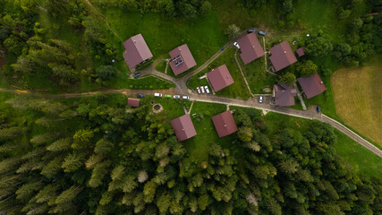 Mountain houses, with solar panels on the roof, through the pine forest in countryside of Carpathian mountains in Ukraine