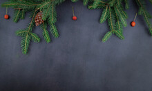 Natural Christmas Background With Green Fir Branches, Pine Cone And Red Berries On Dark Grey Background. Copy Space For Text, Flat Lay, Top View.
