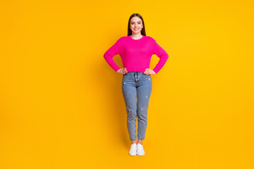 Canvas Print - Full length photo of lovely young woman hands hips look camera wear pink sweater jeans sneakers isolated yellow color background