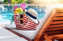 Beach Bag With Accessories On Sun Lounger Near Swimming Pool In Luxury Resort
