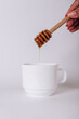 The girl's hand holds a Honey Dipper on a white Cup