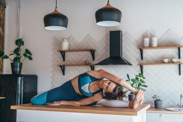 Wall Mural - Woman stretching at home sitting on kitchen table.