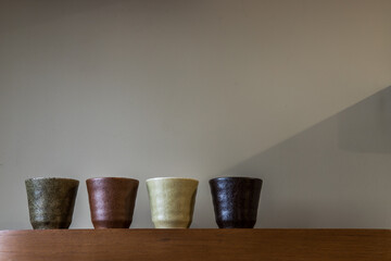 Wall Mural - Four ceramics mugs handmade on the wooden shelf on wall of living room. Home decor. Space for text. No focus, specifically.