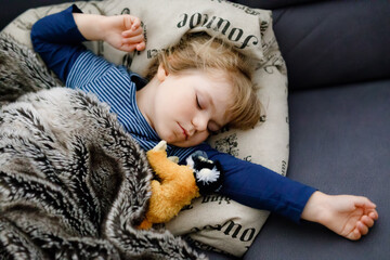 Cute little toddler girl sleeping in bed. Adorable baby child dreaming, healthy sleep of children by day.