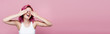 young woman with colorful hair smiling and covering eyes with hands isolated on pink, panoramic shot