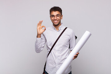 Wall Mural - young architect man feeling happy, relaxed and satisfied, showing approval with okay gesture, smiling