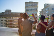 © Trevor Adeline/Caia Image - Young friends drinking beer on sunny urban rooftop