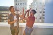 © Trevor Adeline/Caia Image - Happy young couple high fiving on sunny urban rooftop balcony