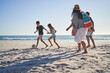 © Trevor Adeline/Caia Image - Family playing soccer on sunny ocean beach