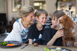 © Paul Bradbury/Caia Image - Happy mother and sons with dog at dinner table