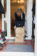 © Paul Bradbury/Caia Image - Woman retrieving produce boxes from front stoop