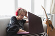 © Paul Bradbury/Caia Image - Boy with headphones and laptop on living room sofa