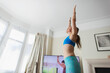 © Paul Bradbury/Caia Image - Woman practicing yoga online in living room