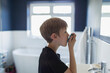 © Paul Bradbury/Caia Image - Boy with asthma using inhaler in bathroom