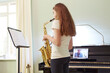 © Adam Gault/Caia Image - Girl taking online saxophone lesson at home