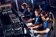 © Friends Stock - Team of professional cybersport gamers wearing headphones participating in eSport tournament while sitting in gaming club or in internet cafe
