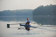 © Dann - Middle aged woman rowing on calm autumn lake at early morning with mist over water.