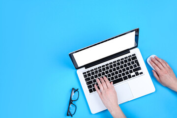 Poster - Woman working on laptop computer and glasses on blue background