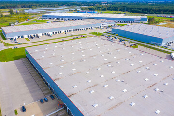 Wall Mural - Aerial drone view of group of large modern industrial warehouse or factory buildings in suburban city area.Logistic transportation cargo terminal