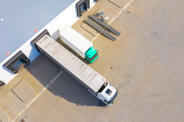 Aerial view of goods warehouse. Logistics center in industrial city zone from above. Aerial view of trucks loading at logistic center