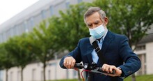 Senior Gray-haired Man In Medical Mask Standing At Bike On Street And Disinfecting Hands With Spray Sanitizer. Old Grandfather Spraying Disinfectionand Cleaning Skin From Germs Outdoors. Disinfector.