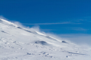 .Snowy mountain slope with wind, winter background