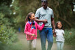 © Paul Bradbury/Caia Image - Happy father and daughters holding hands walking on park path