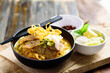 Northern Thai food (Khao Soi), Spicy curry noodles soup with beef eating with crispy deep-fried egg noodles, pickled mustard, shallots, lime and ground chillies fried in oil