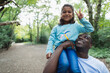 © Paul Bradbury/Caia Image - Portrait father carrying daughter gesturing peace sign in woods