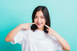 © sorapop - Portrait of Asian teen beautiful young woman smile have dental braces on teeth laughing point finger her mouth, studio shot isolated on a blue background, Medicine and dentistry concept