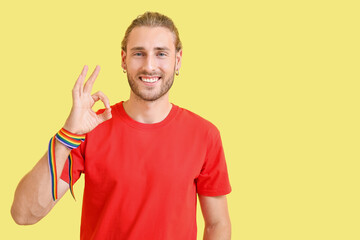 Sticker - Young man with rainbow bracelet showing OK on color background. LGBT concept