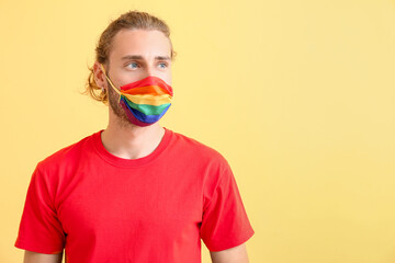 Wall Mural - Young man in rainbow mask on color background. LGBT concept