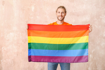 Wall Mural - Young man with LGBT flag on color background