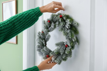 Woman Hanging Beautiful Christmas Wreath On Door